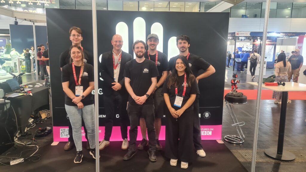 Group photo of Shadow Robot team smiling together at the ICRA 2026 robotics conference in Vienna, standing in front of a conference banner.