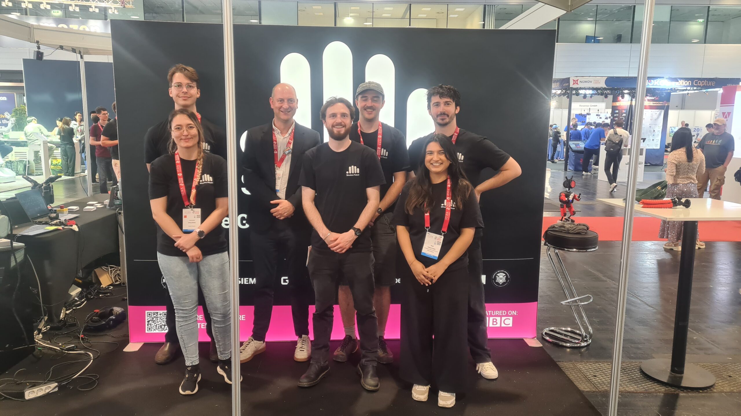 Group photo of Shadow Robot team smiling together at the ICRA 2026 robotics conference in Vienna, standing in front of a conference banner.